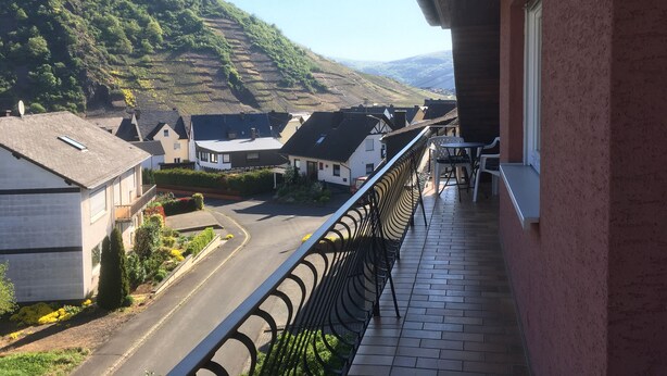 A balcony with a view of a residential street and hilly landscape. - Newly renovated (in 2020) vacation apartment, 4 p., with a great view of the Moselle valley (Briedern)