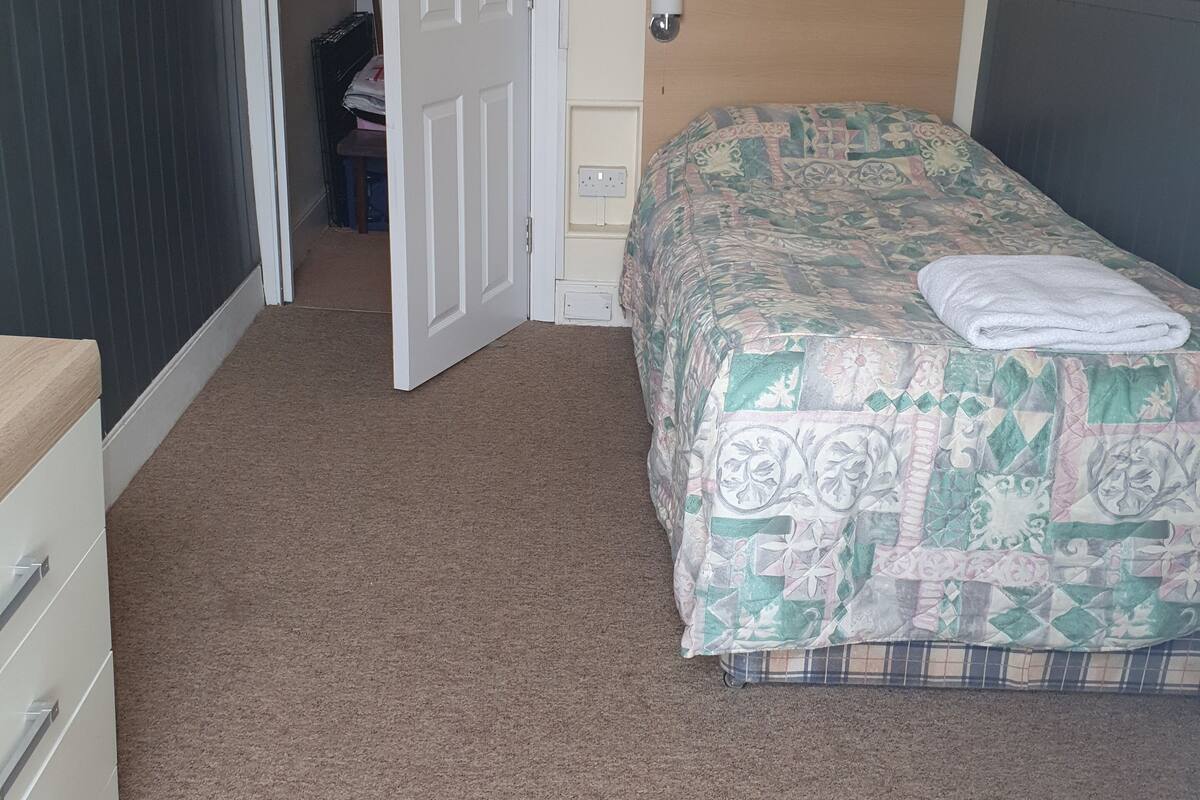 Ein Schlafzimmer mit einem Bett, einem Schminktisch und einer Tür zu einem anderen Raum.