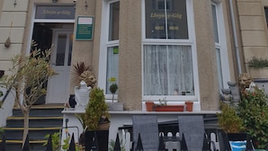 Un edificio en esquina con múltiples ventanas y un letrero que indica que es una casa de huéspedes.
