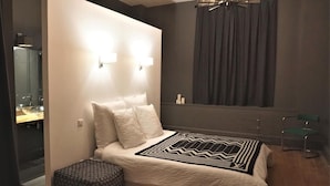 Une chambre à coucher moderne avec un grand lit, une table de chevet, un miroir et une fenêtre avec des rideaux.
