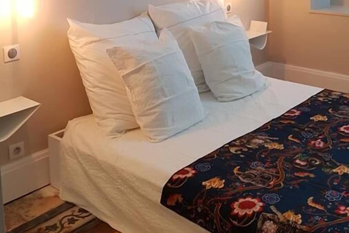 A modern bedroom with a bed, white pillows, a floral bedspread, and a wall-mounted clock.