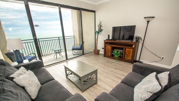 A living room with a sofa set, a coffee table, a TV, and a piano. - Ocean Forest 2309 (Myrtle Beach)