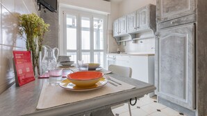 A modern kitchen with white cabinets, a grey refrigerator, and a dining area with a table set for two. - Appartamento con Vista by Wonderful Italy (Torino)