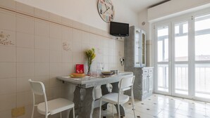 A kitchen with a dining table, chairs, a clock, and a TV. - Appartamento con Vista by Wonderful Italy (Torino)