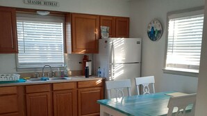 A kitchen with wooden cabinets, a white refrigerator, a sink, and a dining table with chairs. - Heron Cottage - Private & Quaint (Panama City)