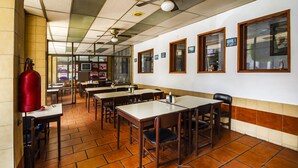 Un restaurante con pisos de baldosas, mesas y sillas de madera, y un extintor.