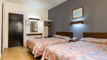 Una camera d'albergo con due letti, una ventola a soffitto, uno specchio, un quadro incorniciato e un comodino con un telefono.