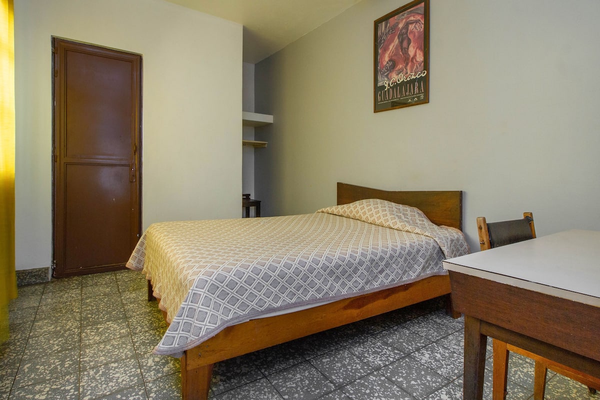 Une chambre à coucher avec un lit en bois, une petite table et une porte.