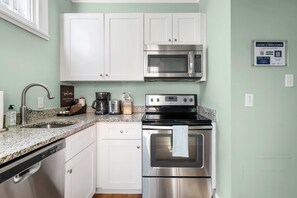 A kitchen with white cabinets, a stainless steel microwave, a toaster, and a dishwasher. - Charming Ground Floor Suite 6 Blocks To King (Charleston)