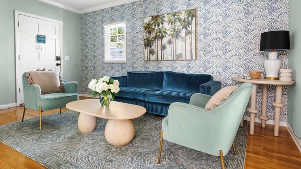 Un salon avec un canapé bleu, une table basse ronde et un tapis à motifs.