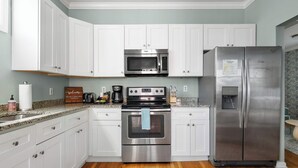A modern kitchen with white cabinetry, stainless steel appliances, and a granite countertop.