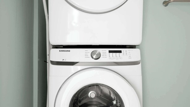 A Samsung front-loading washer and dryer stacked vertically in a laundry room.