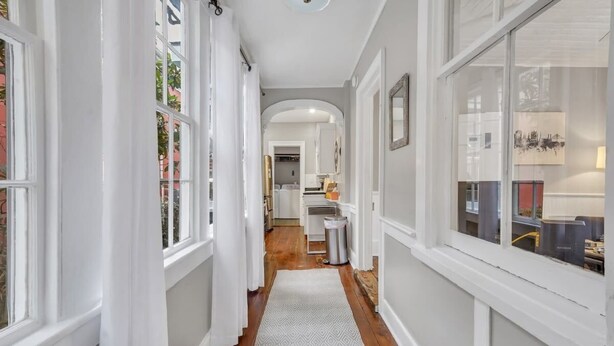 A narrow hallway with white trim, a patterned rug, and a view into a kitchen area.