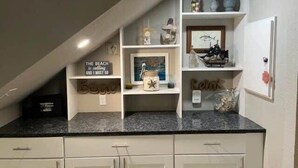 A kitchen with white cabinets, a granite countertop, and decorative items including a sign that says "The beach is calling and I must go." - Totally Beachin! - One Block from beach - Unit 1101 - Island Dunes Condo's (Port Aransas)