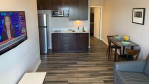 A modern kitchen with dark cabinets, a stainless steel refrigerator, and a microwave. - Newer private apart-hotel suite in Old Town (San Diego)