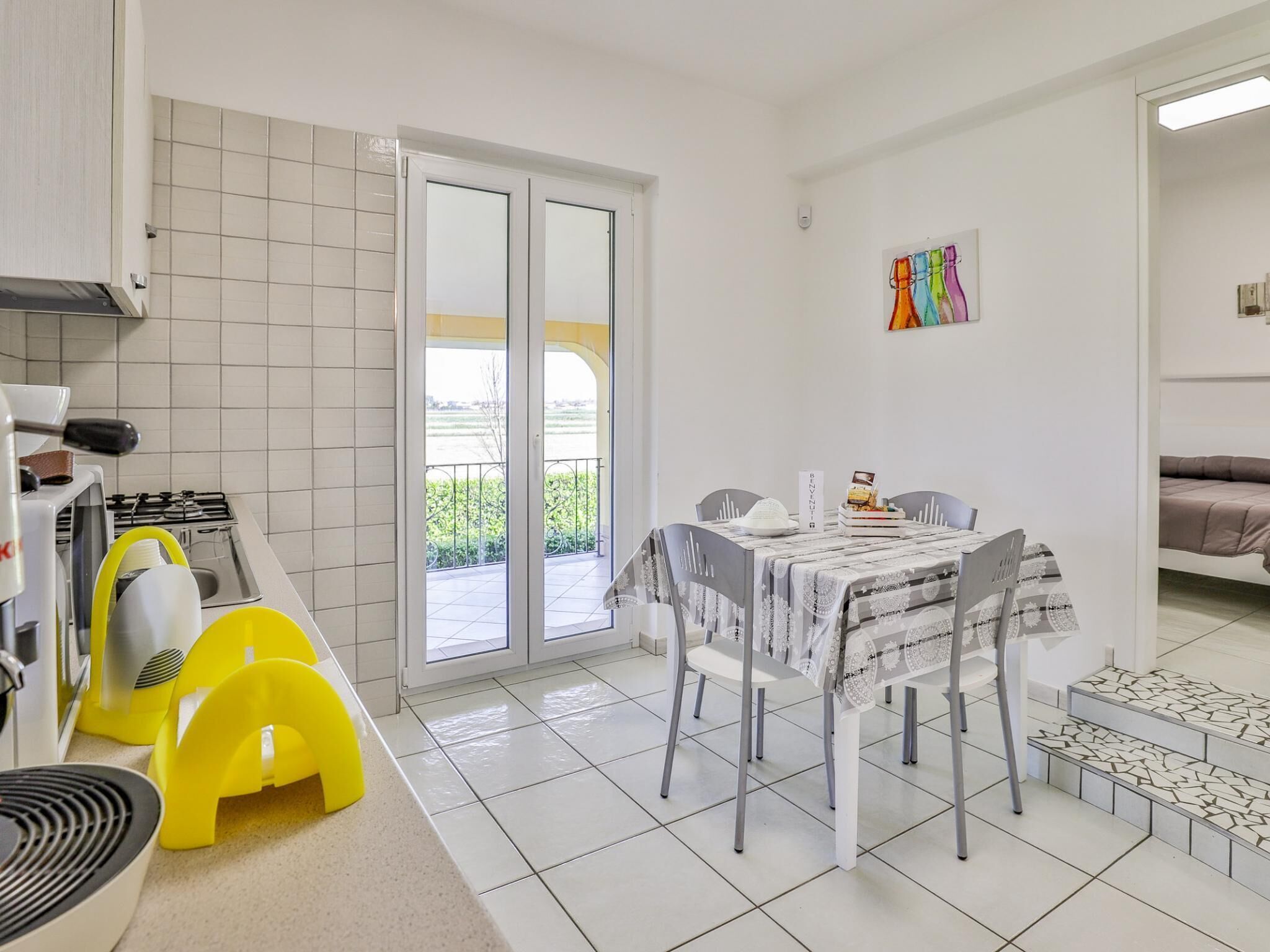 Une cuisine moderne équipée d’une cuisinière à gaz, d’ustensiles de cuisine jaunes et d’un coin repas avec une table et des chaises.