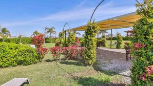 Um jardim bem cuidado com pérgola, área de estar e diversas plantas.