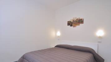 Een slaapkamer met een bed, twee wandlampen en een stadsgezicht op de muur.
