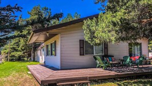 A single-story house with a deck, surrounded by trees. - Village House at Valley Village (Irwin)