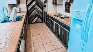 A compact kitchen with a herringbone-patterned backsplash, a built-in oven, and a blue refrigerator. - Village House at Valley Village (Irwin)