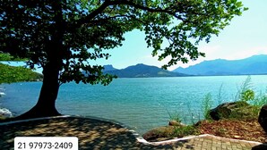 Un’area pavimentata con un grande albero e vista su un lago e montagne.