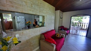 Un soggiorno con parete in pietra, un divano rosso, soffitto in legno e vista del balcone esterno.