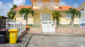 A yellow building with a red-tiled roof, a gated entrance, and a stone wall. - Villa Salines (sleeps 15) Sainte-Anne Jacuzzi Pool, 5 minutes from Pointe Marin (Sainte-Anne)