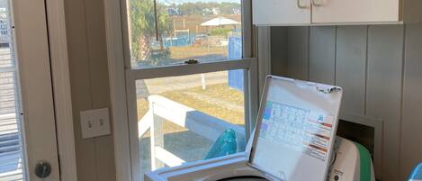 A laundry room with a front-loading washing machine, a window, and a door.
