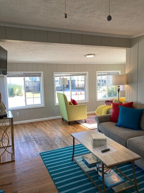 A living room with a sofa, armchair, and coffee table. There are large windows with a view of the outside. - Great Views of Both Inlet & Ocean! 2BR/2BA - Pet Friendly UP Across from beach. (Garden City)