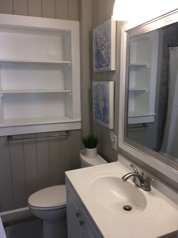 A bathroom with a white sink, a mirror, a toilet, and a shelf above the toilet. - Great Views of Both Inlet & Ocean! 2BR/2BA - Pet Friendly UP Across from beach. (Garden City)