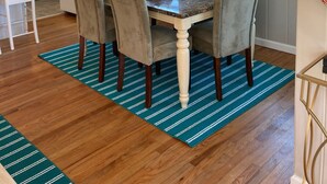 Un comedor con una mesa de mármol, cuatro sillas, un ventilador de techo y una cocina al fondo.