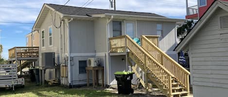 A two-story house with a wooden deck, a staircase, and a small shed.