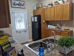 A kitchen with wooden cabinets, a black refrigerator, a sink, and a countertop with a blue water bottle. - The Southern Comfort (Pigeon Forge)
