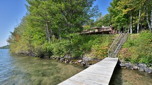 A wooden dock leading to a house surrounded by trees and a lake. - Lake Shore Home with private dock and large deck--1 mile from Bayfield (Bayfield)