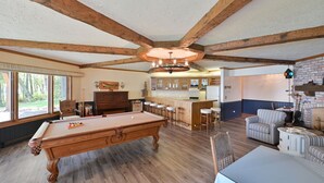 A pool table in a room with wooden beams, a bar area, and a seating area with striped chairs. - Lake Shore Home with private dock and large deck--1 mile from Bayfield (Bayfield)