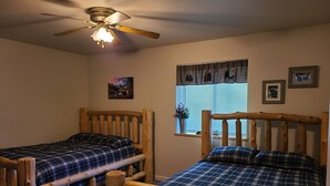 A bedroom with two wooden bunk beds, a ceiling fan, and a window with blinds. - Your Home Away from Home in the Heart of the Kenai Peninsula (Soldotna)