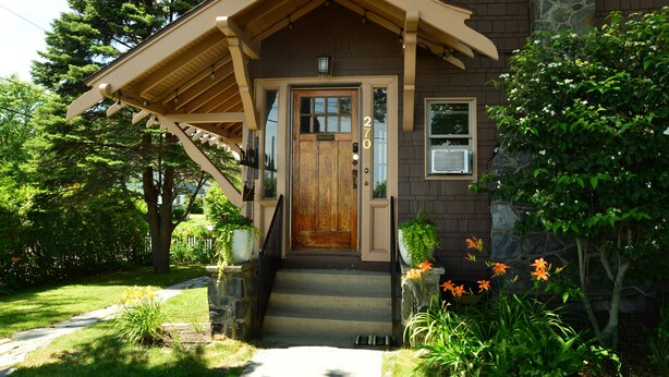 A house with a wooden front door, a stone staircase, and a porch with a wooden railing. - Spacious Craftsman w/ Casco Bay Views. Hot Tub, Patio, Easy Access to Old Port (Portland)