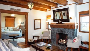 A cozy living room with a fireplace, a television mounted above it, and a sign indicating the location as Portland, Maine. - Spacious Craftsman w/ Casco Bay Views. Hot Tub, Patio, Easy Access to Old Port (Portland)