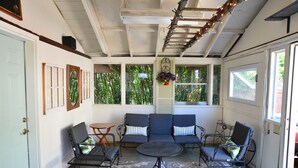 A covered porch with a seating area, a small table, and a decorative hanging. - Spacious Craftsman w/ Casco Bay Views. Hot Tub, Patio, Easy Access to Old Port (Portland)
