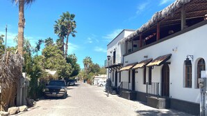 A cobblestone street lined with palm trees and a white building with a tiled roof. - Loreto80-NEW Studio Nopal, in downtown by beach (Loreto)