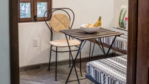 A dining area with a table, chairs, and a window with a view of greenery. - Loreto80-NEW Studio Nopal, in downtown by beach (Loreto)