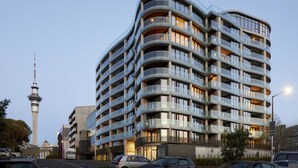 A multi-story hotel with a curved facade, balconies, and a view of a tower in the background. - Amazing Grace Apartment with Heatpump and Carpark (Auckland CBD)