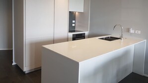 A modern kitchen with a central island, built-in appliances, and a sleek design. - Amazing Grace Apartment with Heatpump and Carpark (Auckland CBD)