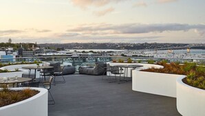 A rooftop terrace with outdoor seating, a view of a marina, and a bridge in the distance. - Amazing Grace Apartment with Heatpump and Carpark (Auckland CBD)