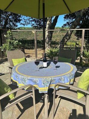 Un patio al aire libre con una mesa redonda, sillas y una botella de vino.