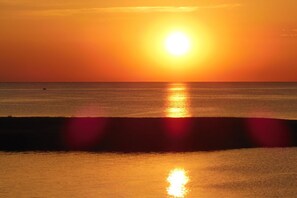 A sunset over a calm sea with a boat in the distance. - Soundfront Dog Friendly Home w/ Hot Tub, Game Room, Private Boat Dock, Kayaks (Avon)