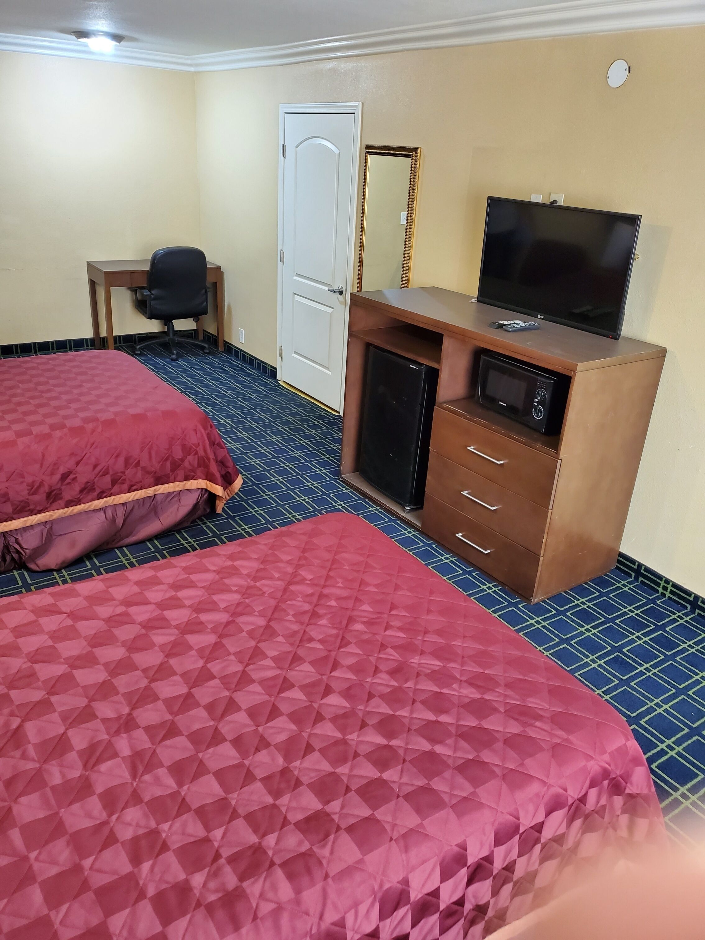 Habitación de hotel con dos camas, un escritorio, televisor y microondas.