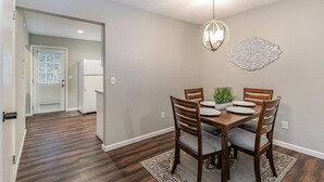 Un coin repas comprenant une table ronde, quatre chaises en bois, un lustre et un élément décoratif mural.