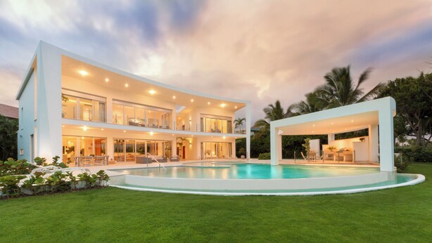Una casa moderna de dos pisos con piscina, ventanas amplias y un espacio exterior cubierto.