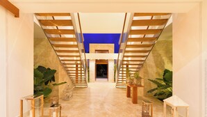 Un interior moderno con piso de mármol, escalera de madera y plantas en macetas.